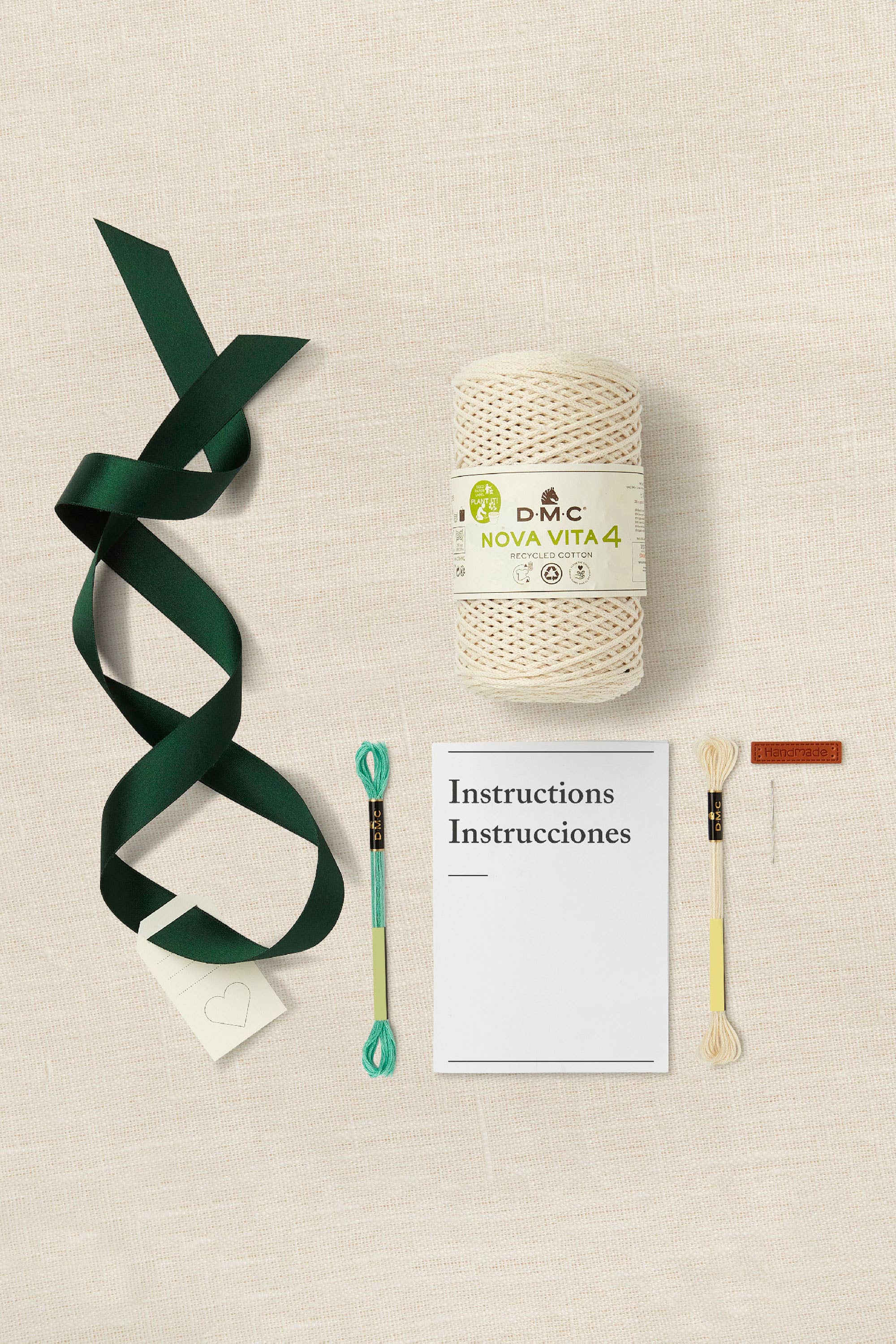 DMC Nova Vita 4 yarn ball with green ribbon, needle, and instructions on a beige background
