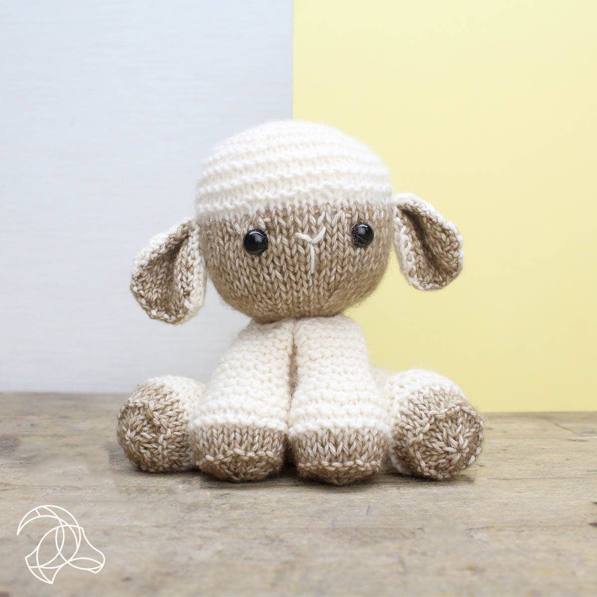 Knitted toy sheep on a wooden surface with a light background