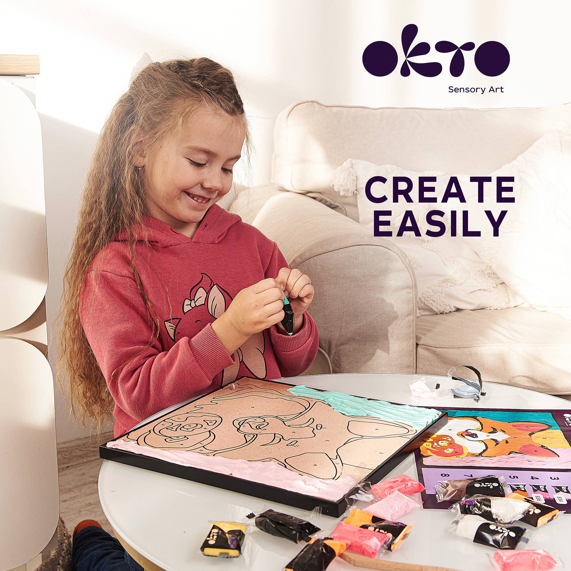 Child engaged in art activity with 'Okto Sensory Art' products on a table.