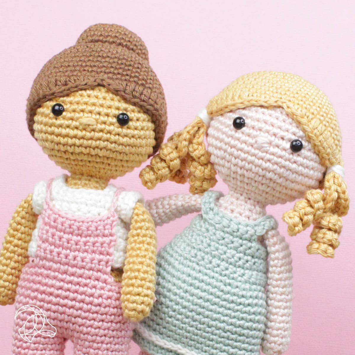 Two crochet dolls with different hairstyles on a pink background