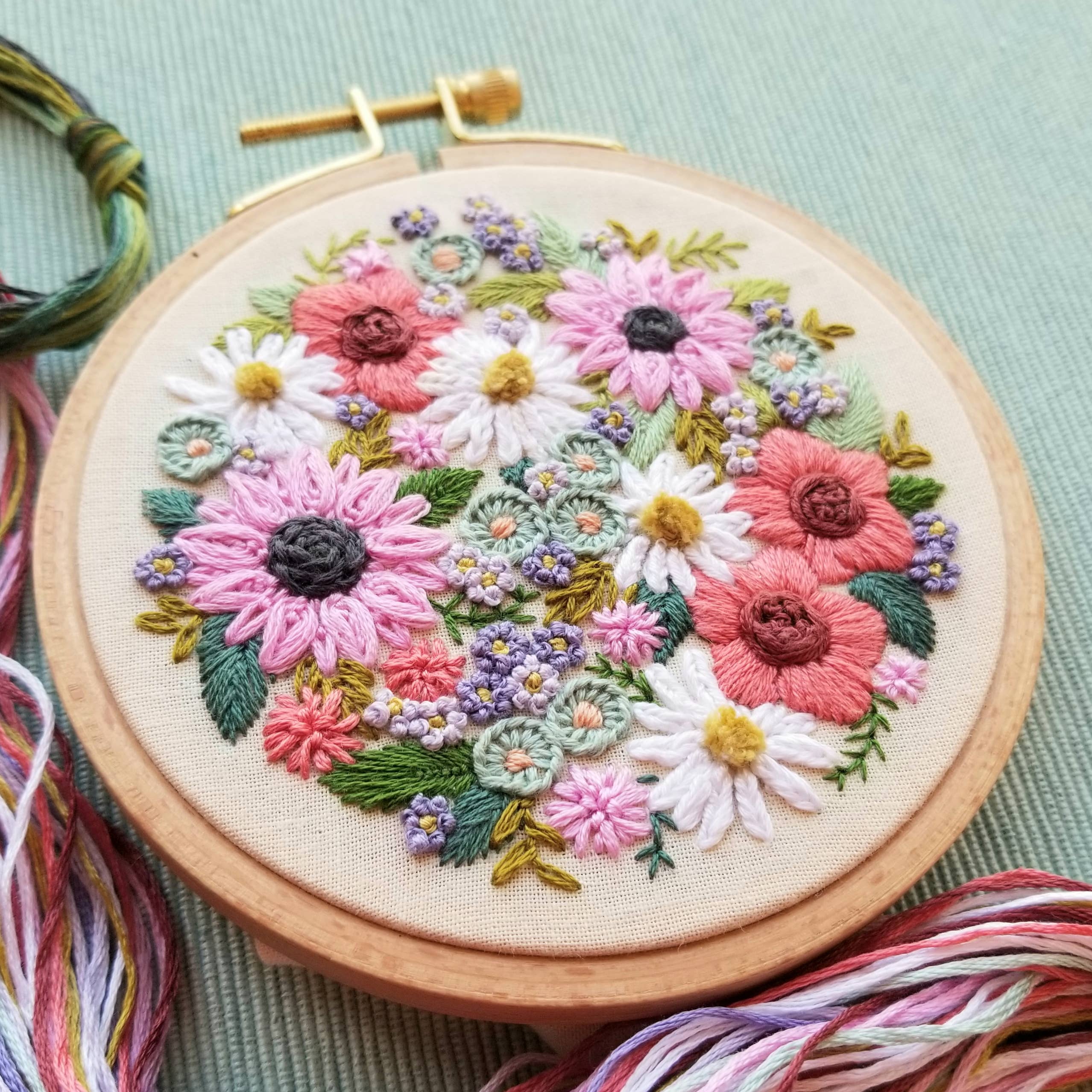 Embroidery hoop with floral design on a light green fabric background