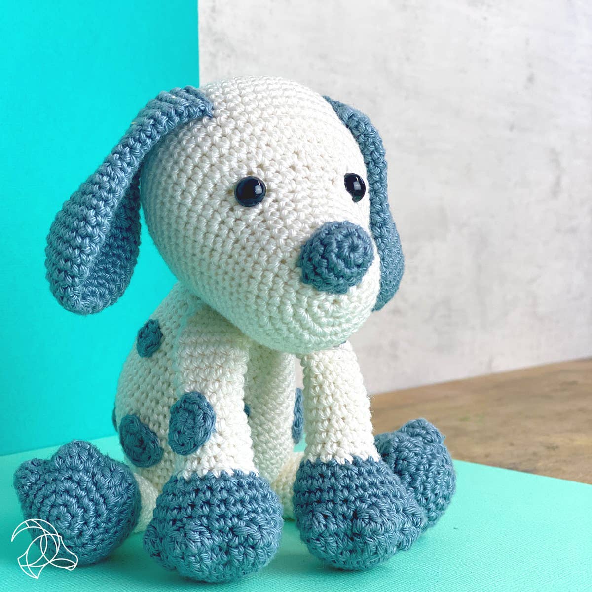 Crocheted dog toy with blue and white colors on a teal and white background