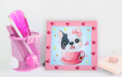 Framed artwork of a dog with a bow on a pink border next to a pink holder with utensils.