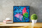 Colorful butterfly artwork on a wooden table with a plant and books.