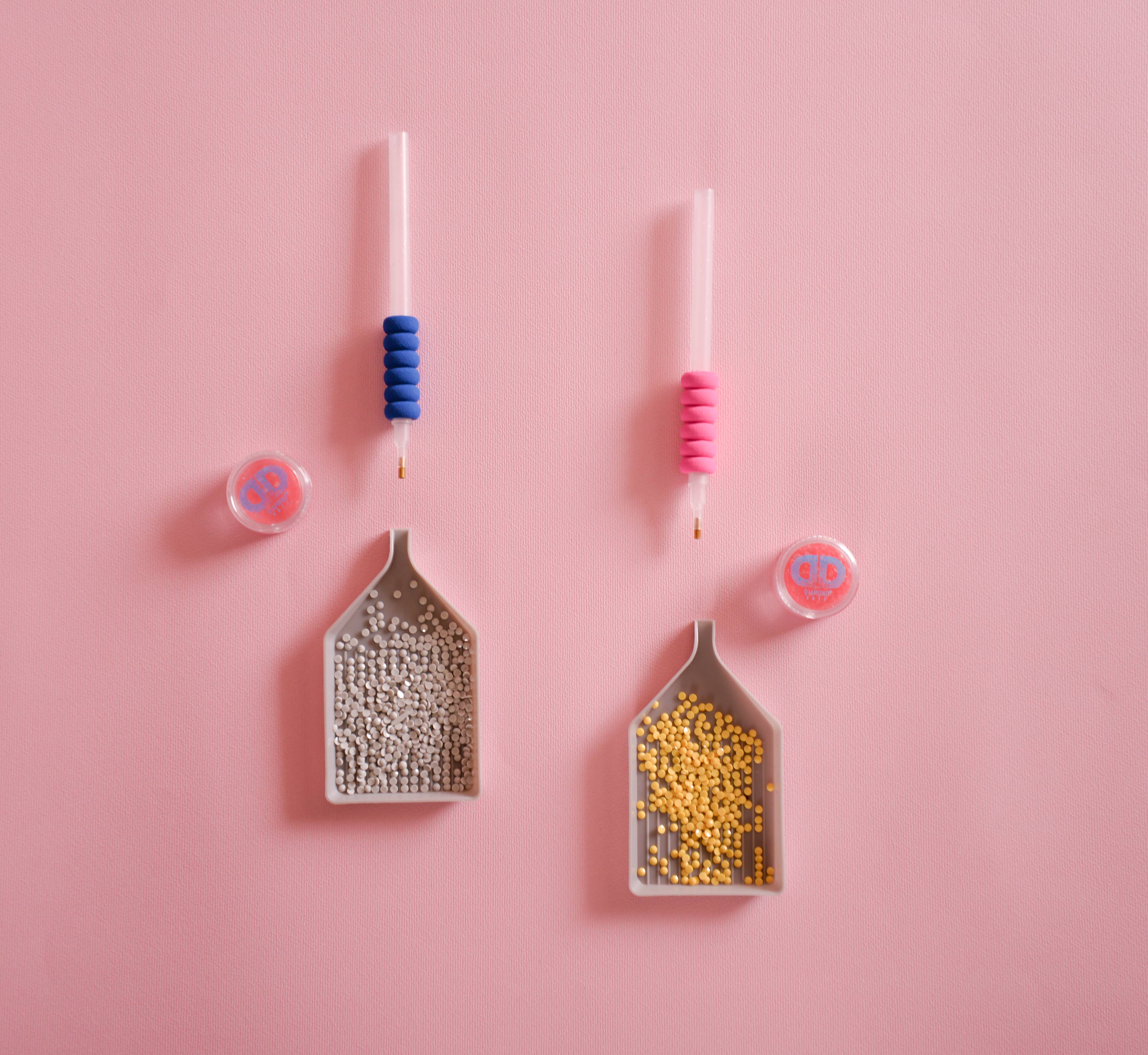 Two small scoops with colorful handles on a pink background