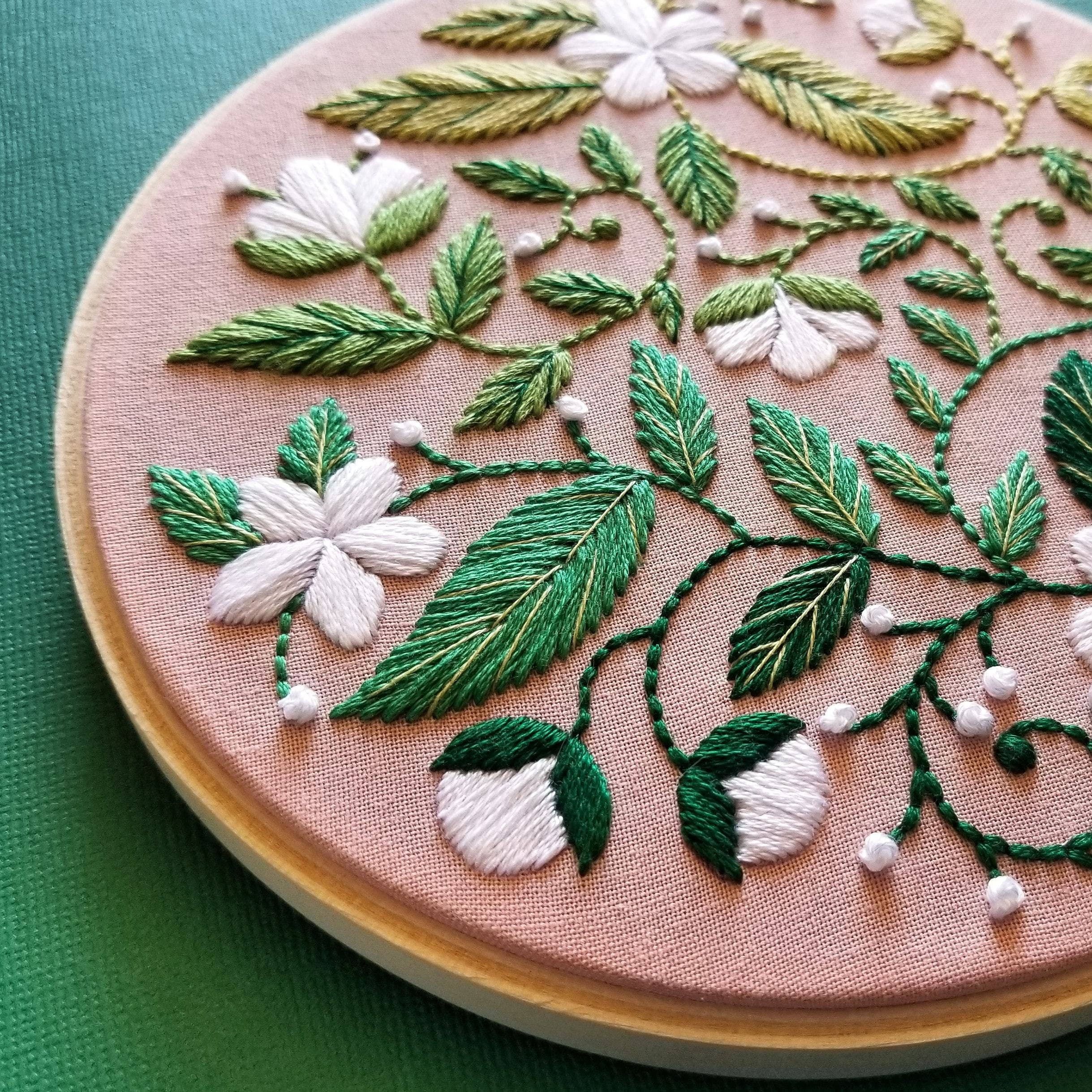 Embroidery hoop with floral and leaf pattern on a green background