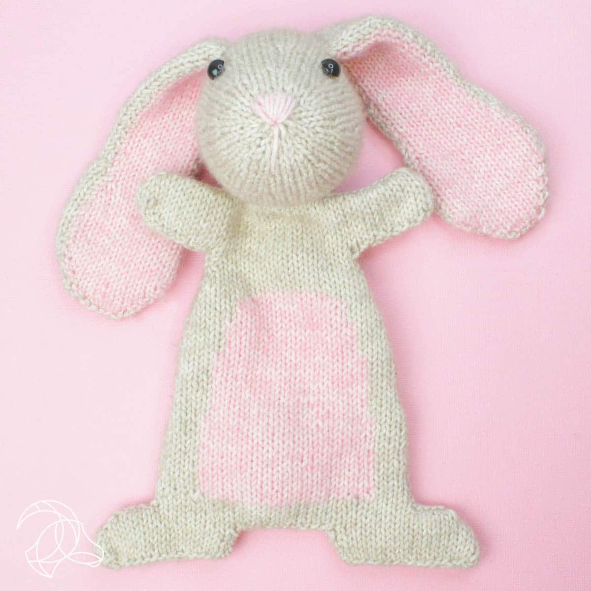 Knitted bunny toy on a pink background