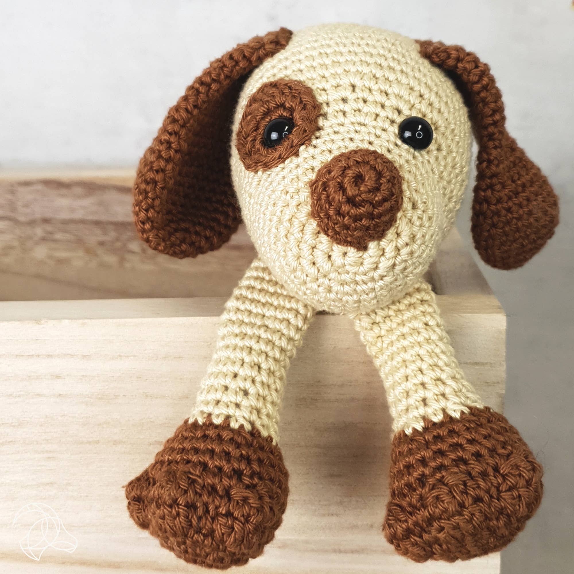 Crocheted dog toy with brown and beige colors on a wooden surface