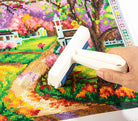 Hand using a tool on a partially completed diamond painting project