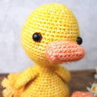 Close-up of a yellow crochet duck with a pink beak on a white background
