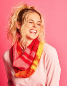 Person wearing a colorful scarf against a pink background