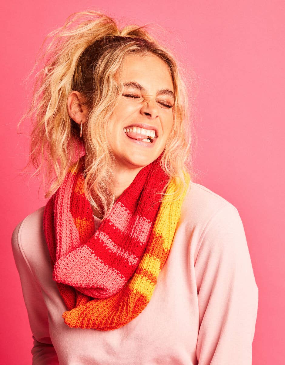 Person wearing a colorful scarf against a pink background