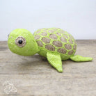 Knitted turtle toy on a wooden surface with a light gray background