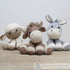 Three knitted farm animal toys (sheep, horse, donkey) on a wooden surface with a light background.