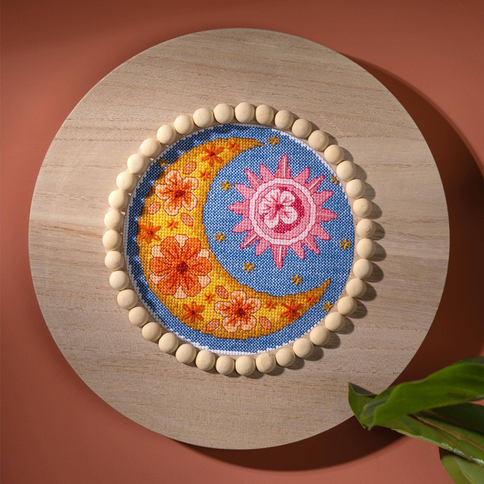 Embroidered patch with floral design on a wooden board against a red background