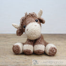 Knitted toy moose on a wooden surface with a light gray background