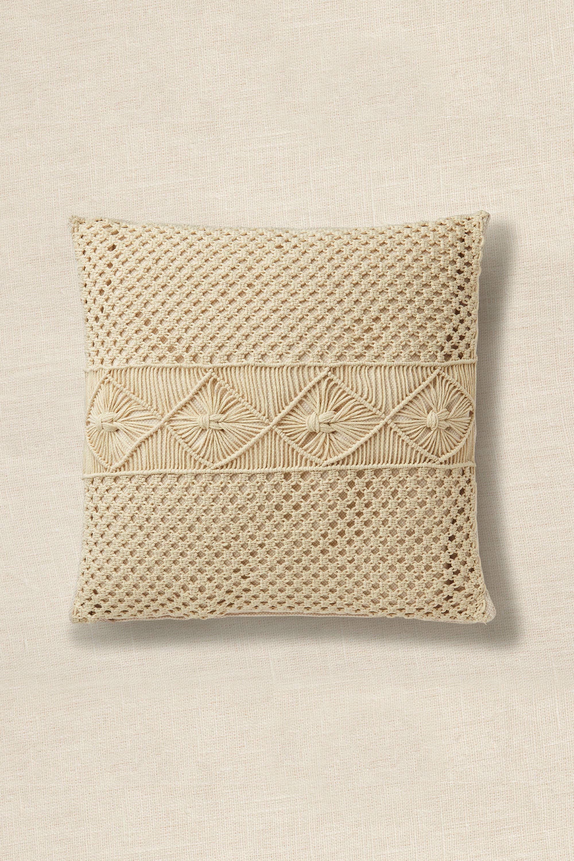 Beige woven pillow with decorative pattern on a beige background