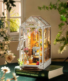 Miniature garden house model on a book with plants and flowers around
