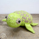 Knitted turtle toy on a wooden surface with a white background