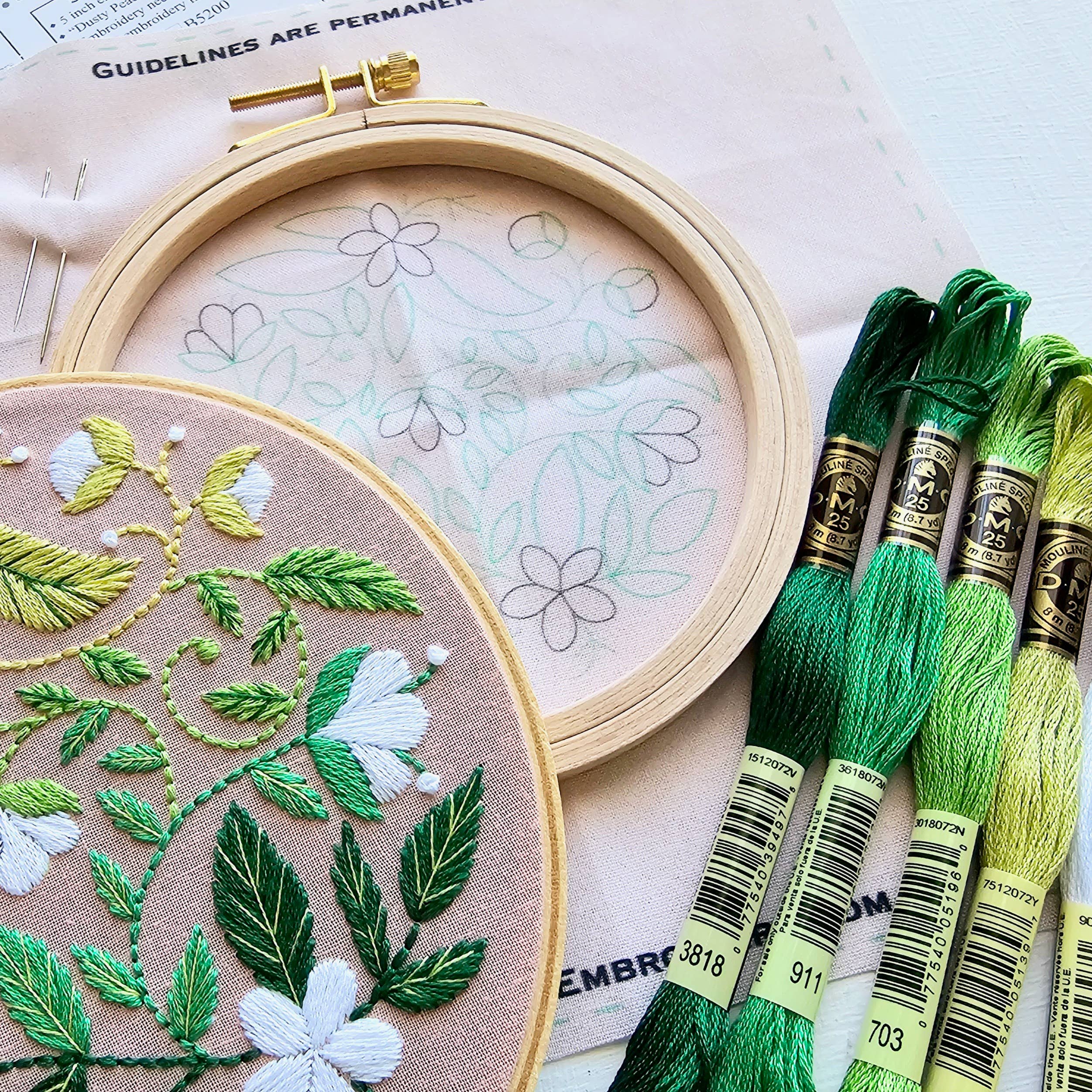 Embroidery hoop with floral patterns and green embroidery threads.