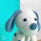 Crocheted dog toy with blue ears and nose against a teal background