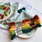 Embroidery hoop with colorful thread skeins and a partially completed floral embroidery design.