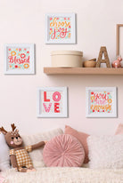 Decorative wall with framed quotes, a teddy bear, and pillows on a couch.