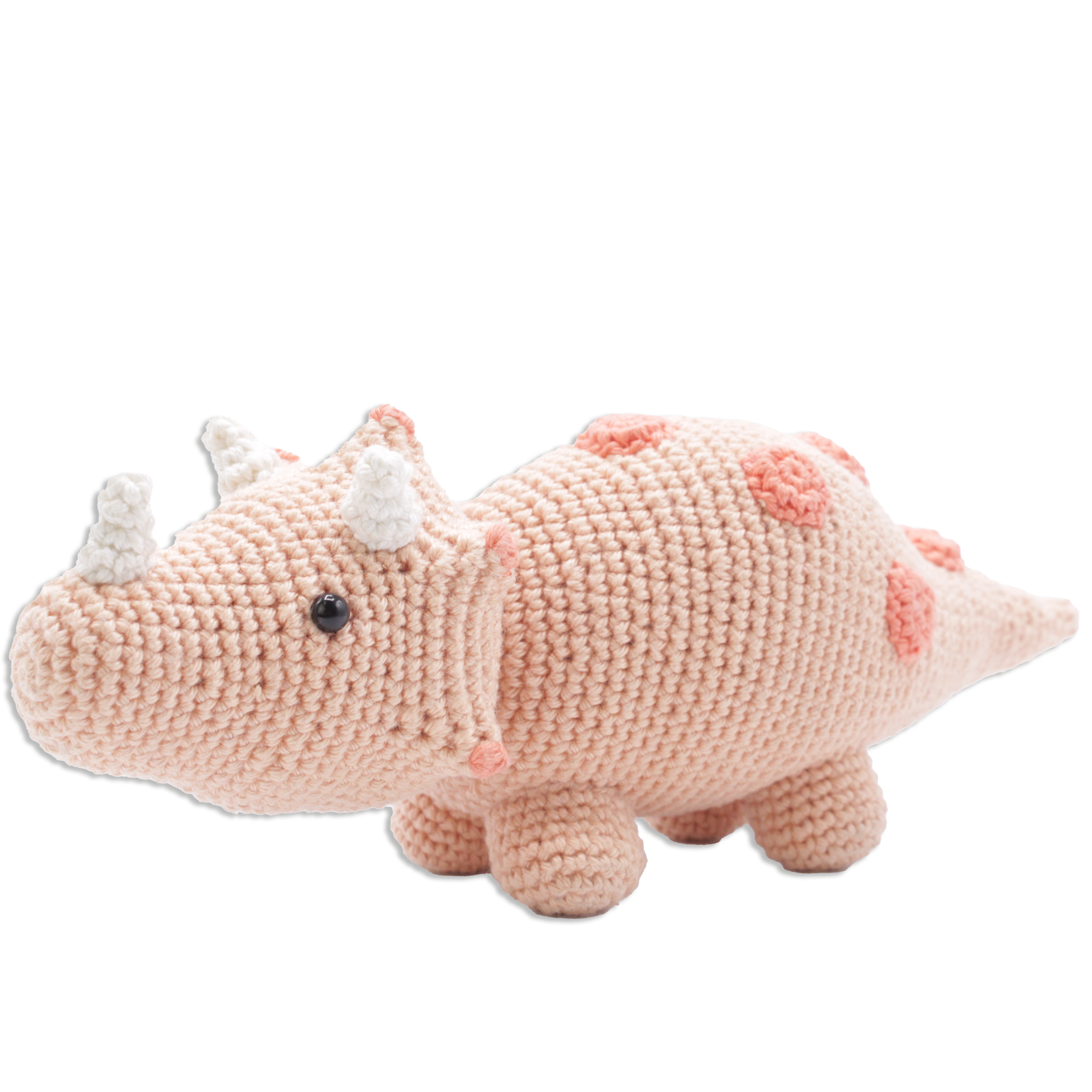 Crocheted dinosaur toy with pink body and white spikes on a white background