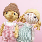 Two crochet dolls with different hairstyles on a pink background