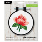 Embroidery hoop with a red rose design on a white background, featuring Bucilla branding.