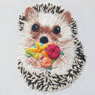Embroidered patch of a hedgehog with flowers on a light gray background