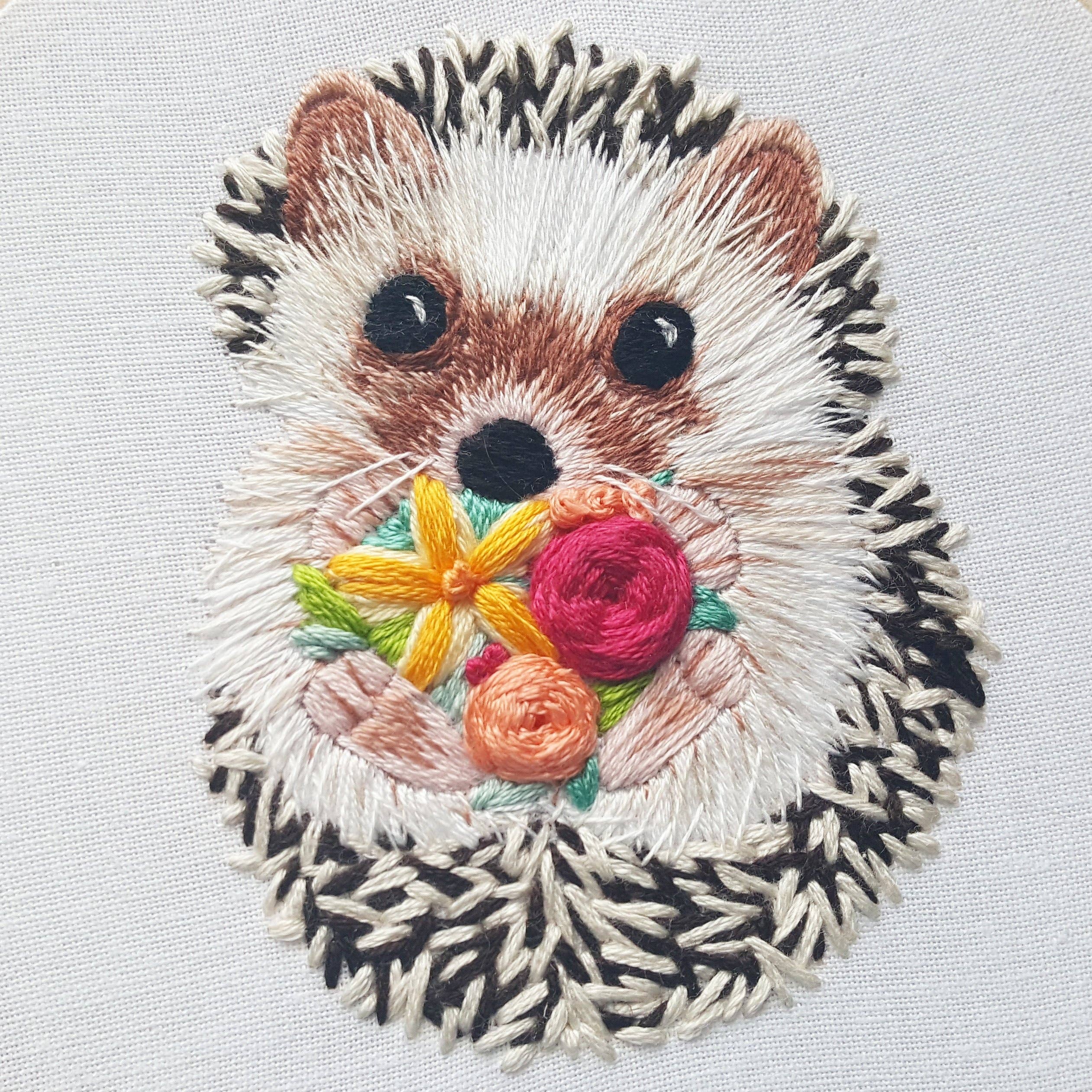 Embroidered patch of a hedgehog with flowers on a light gray background