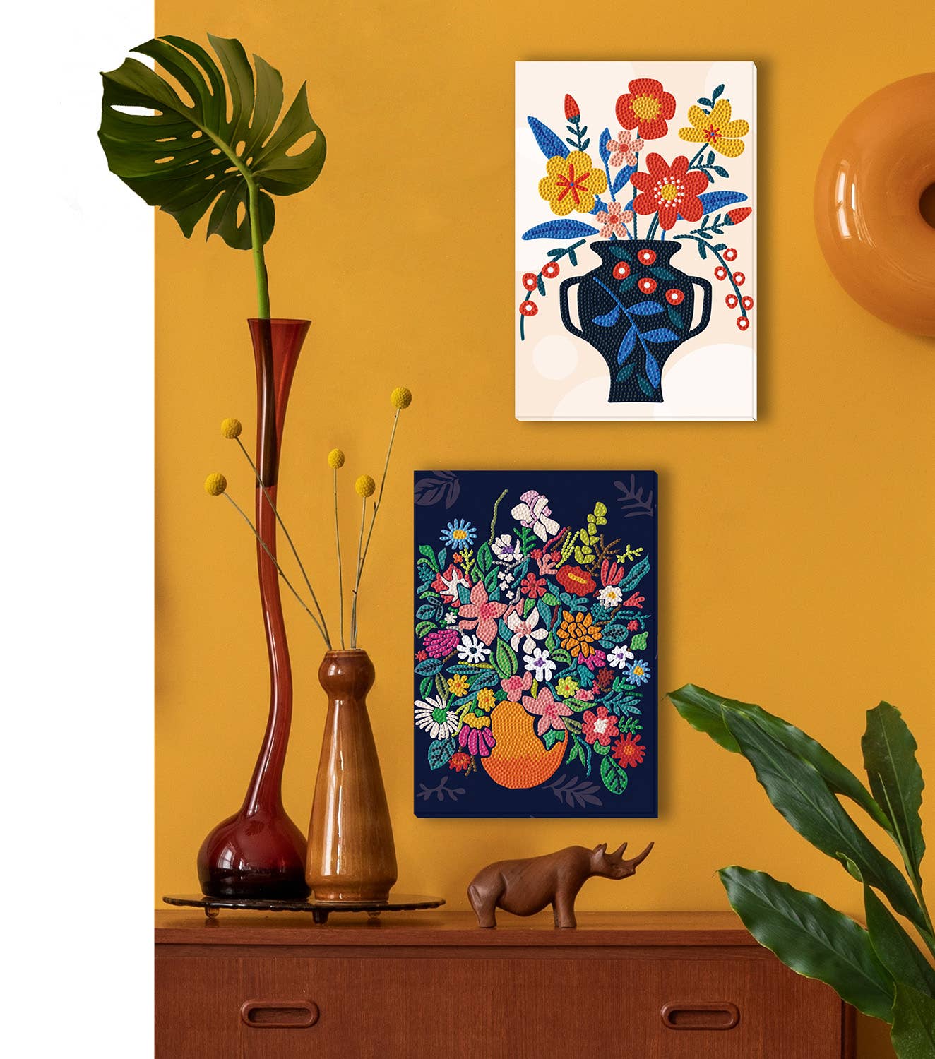 Decorative scene with floral artworks, vases, and a rhinoceros figure on a yellow wall.