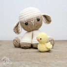 Knitted sheep and duckling toy on a wooden surface with a light gray background