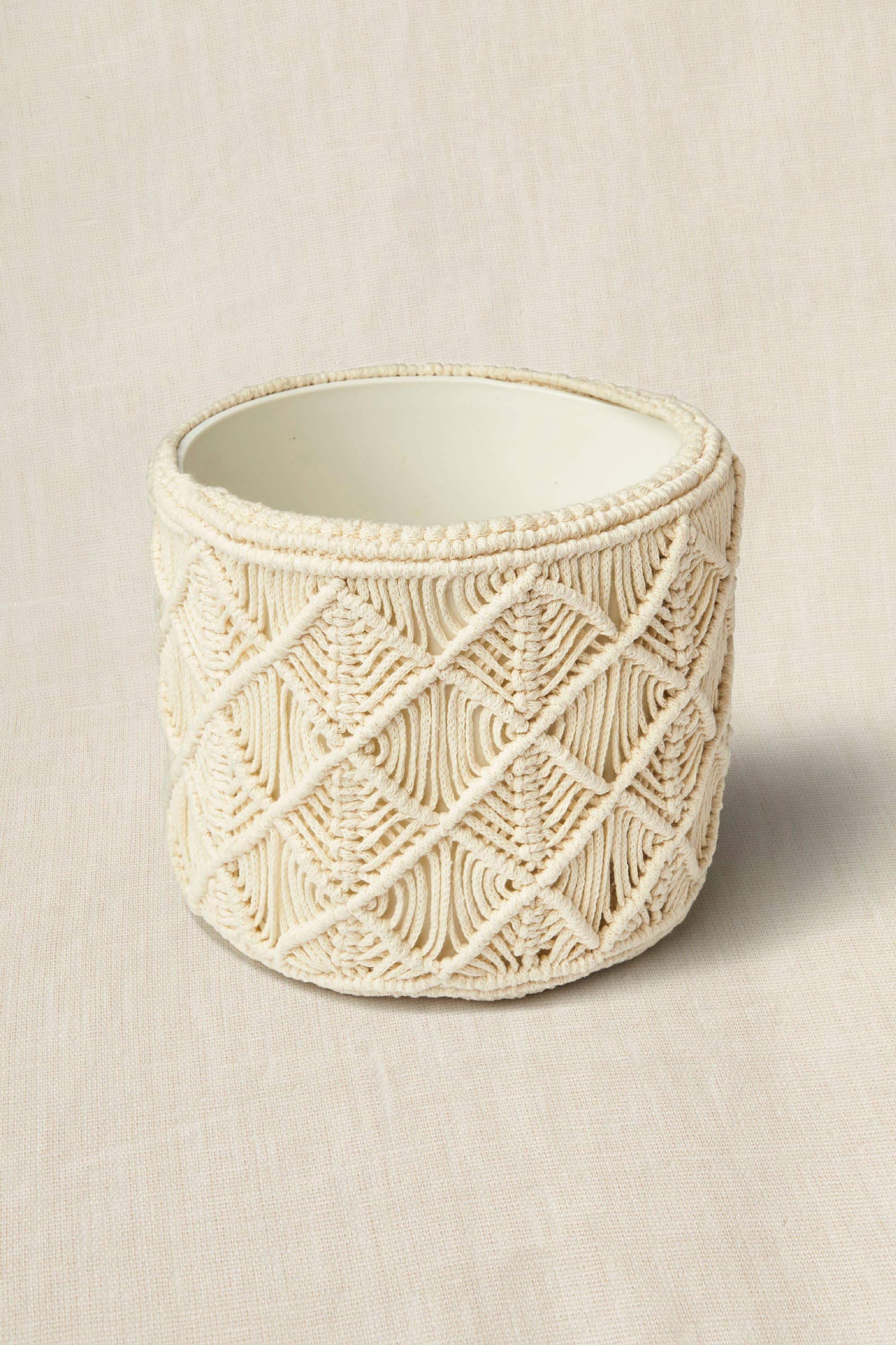 Decorative pot with macrame pattern on a beige background