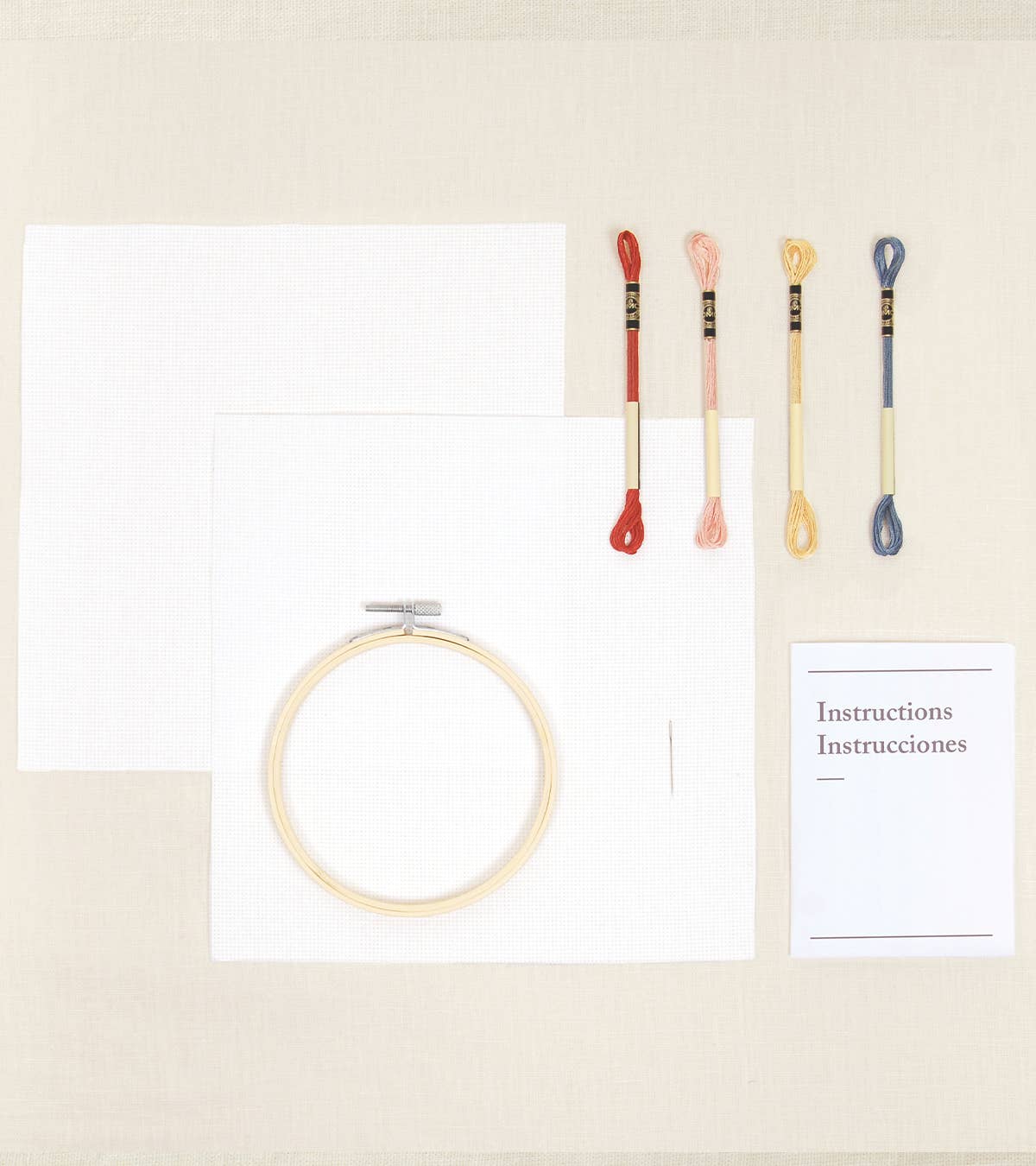 Embroidery hoop, colorful needles, and a paper with text on a beige background