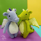 Two crocheted dragon toys, one purple and one green, on a colorful background.