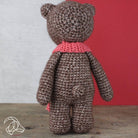Brown teddy bear with a pink scarf against a red and gray background