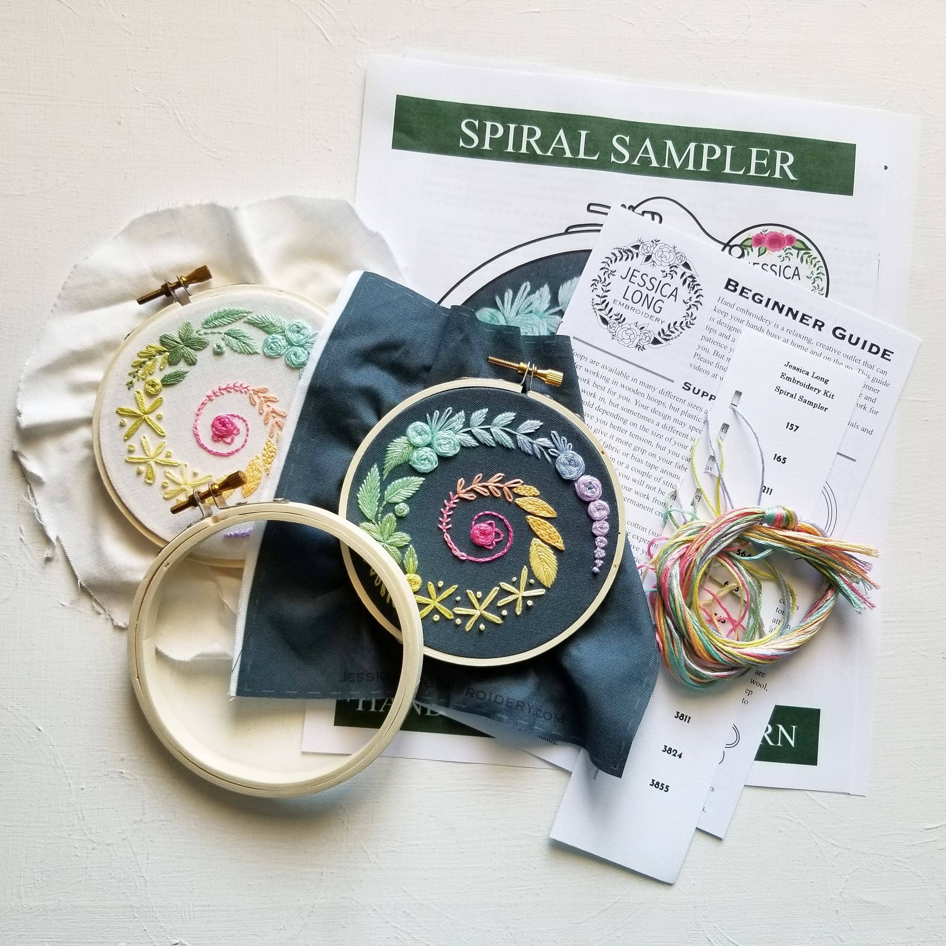 Embroidery kit with completed pieces, fabric, and instructions on a light surface
