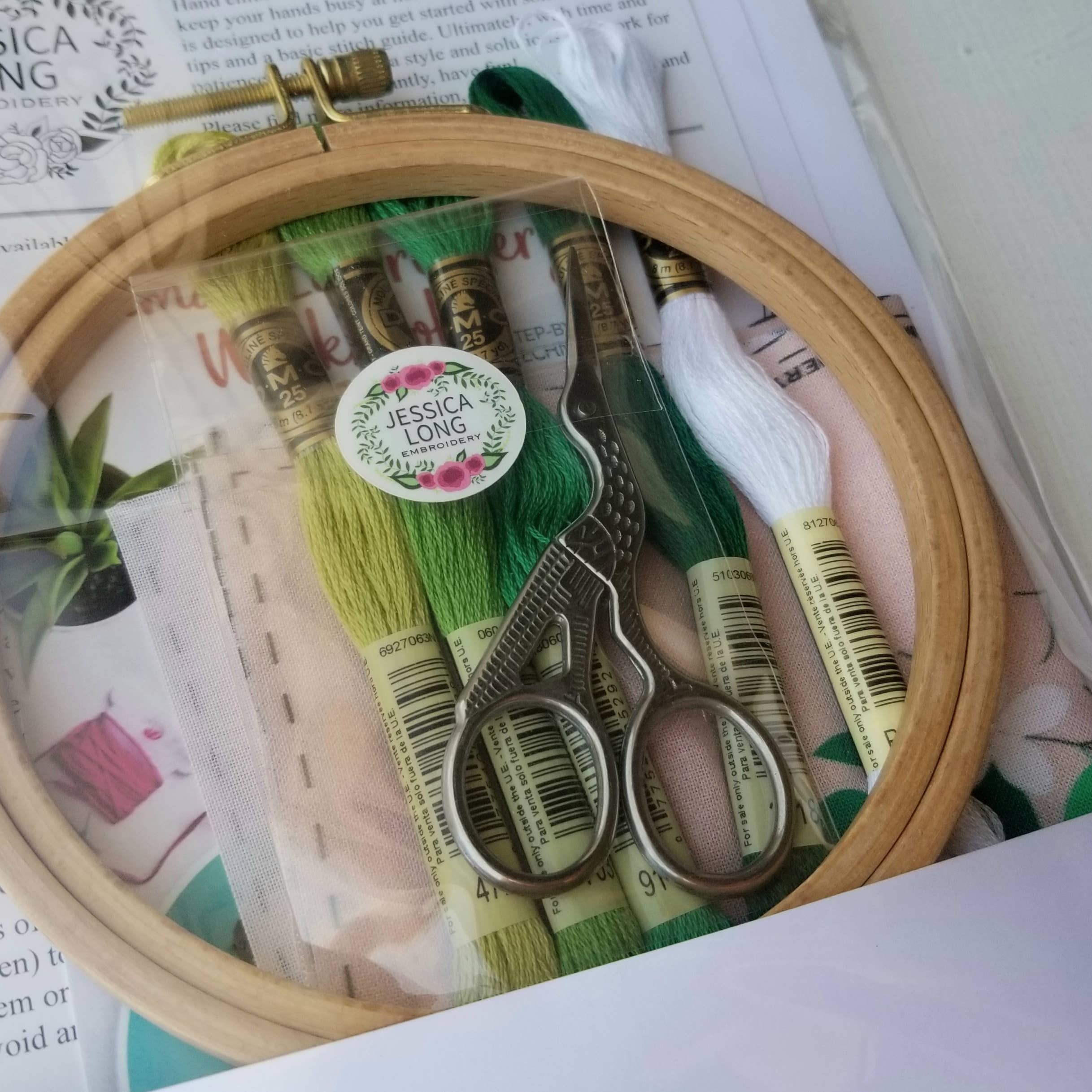 Embroidery hoop with scissors and thread on a magazine background