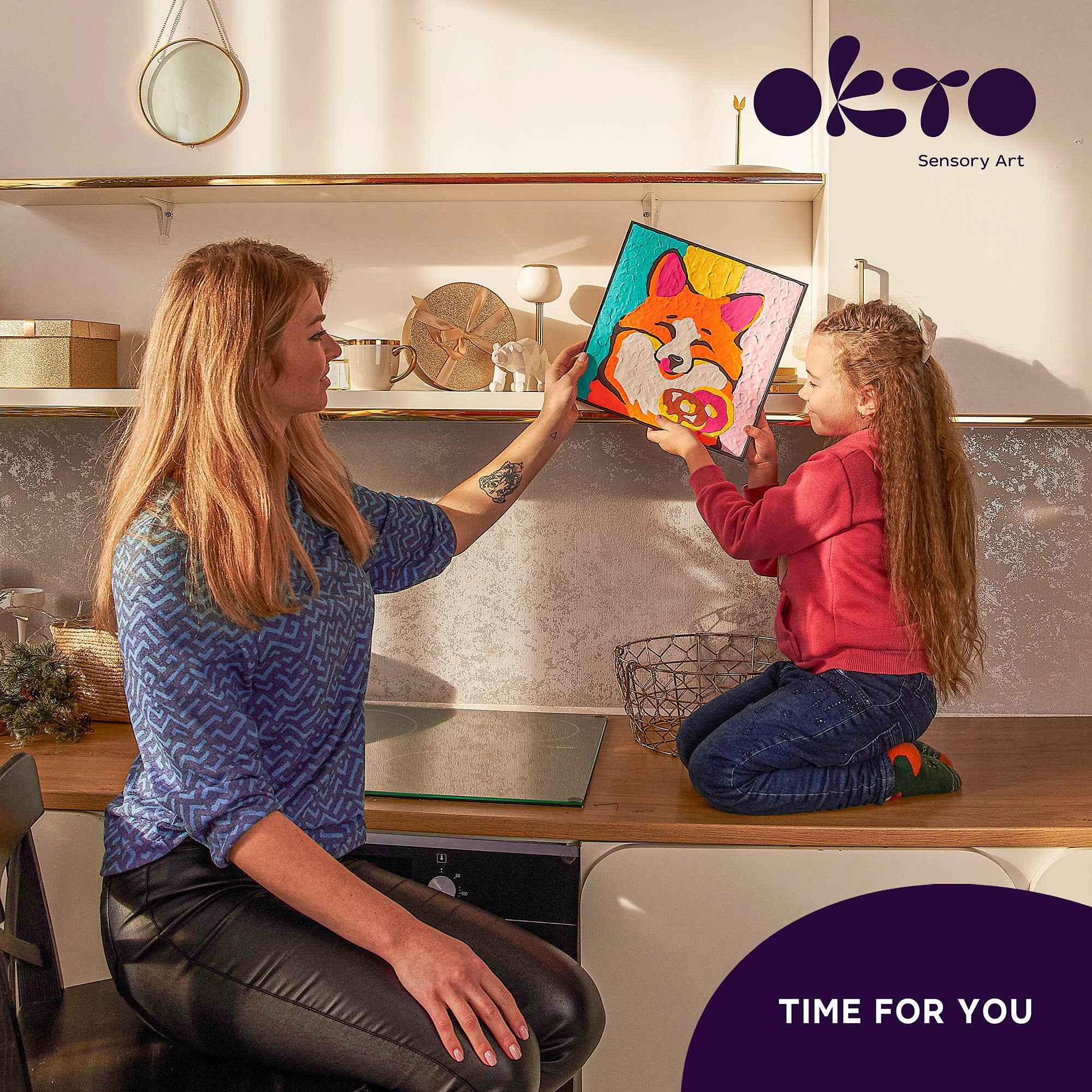 Woman and child in a kitchen looking at a colorful toy together, with 'OKTO' branding.